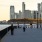 people walking on a sidewalk near a body of water and a city
